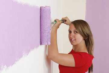 Junge Frau streicht eine Wand