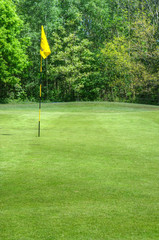 Obraz premium Vibrant image of golf course with flag and fairway in sun
