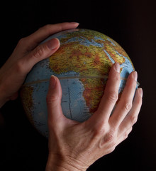 mano sujetando una bola del mundo sobre fondo negro