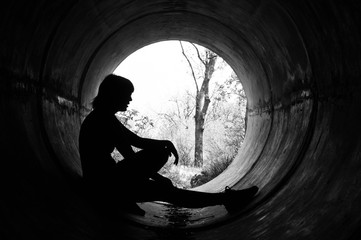 Silhouette of a young girl in sewer pipe