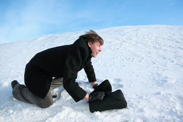 Young man creeps on all fours on snow with  brief-case