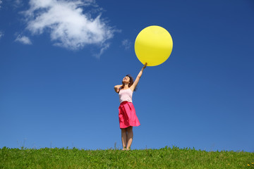 Woman stands in summer in field holds  balloon and looks in sky