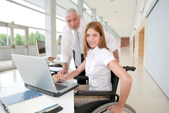 Woman in wheelchair with trainer in office