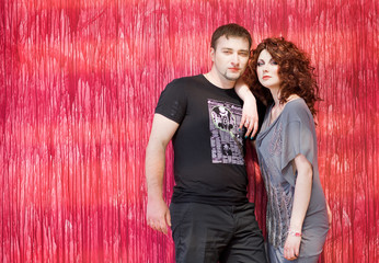romantic young couple standing together near red background