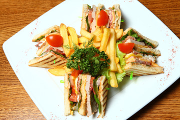 Sandwich with ham and fried potatoes on a white plate