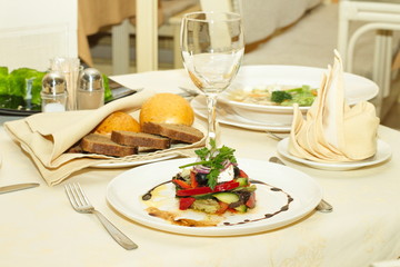 Table covered at restaurant with salad in the foreground