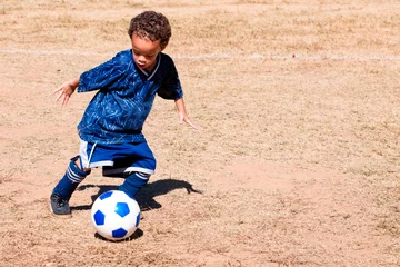 Foto op Plexiglas Young African American boy playing soccer. © Robert Hainer