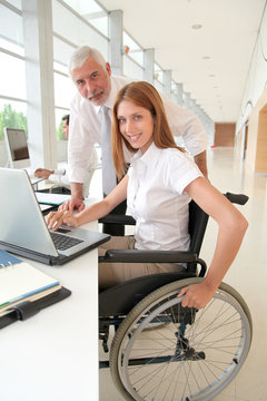Woman in wheelchair with trainer in office