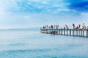 People fishing on a pier - obrazy, fototapety, plakaty