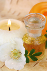 Fototapeta na wymiar Wellness mit Massageöl, Duftkerzen und Wildrosenblüte