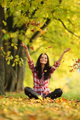 woman drop leaves in autumn park
