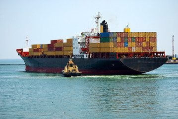 The small tugboat accentuates the size of the large container sh