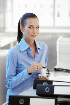 Smiling office girl having coffee