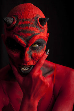 Red devil woman contemplating evil. Low key lighting.
