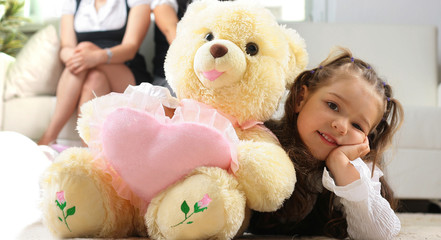 Little girl is hugging big teddy bear