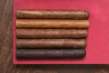Five cigars on a red background.