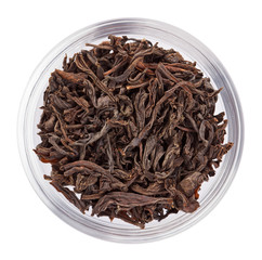 Black leaf tea heap in transparent glass bowl, isolated on white
