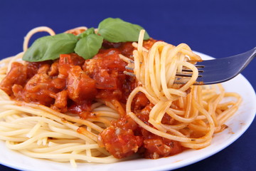 Spaghetti bolognese on a plate being eaten with a fork