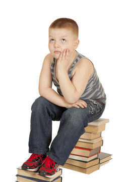 boy sitting on the books of his head in his hand