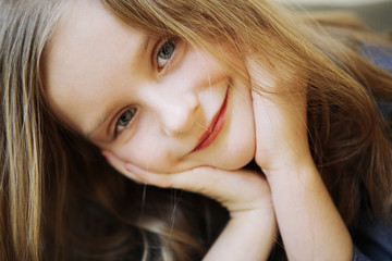 Portrait of small happy girl with long blond hair.
