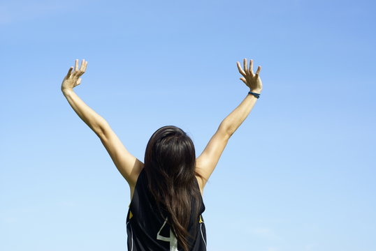 Happy teen girl with outstretched arms and blue sky