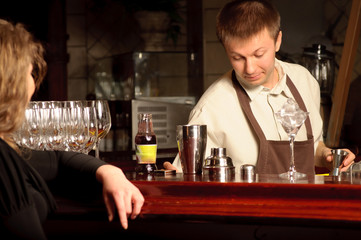 A girl near the bar with a barman - indoors