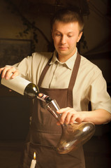 A sommelier pouring red wine into decanter