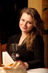 Beautiful young woman sitting with a wineglass in the restaurant