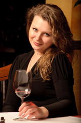 Beautiful young woman sitting with a wineglass in the restaurant