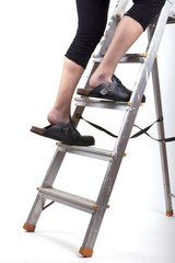 studio shot of a woman standing on a ladder with big shoes