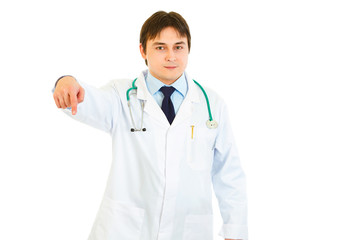 Fototapeta premium Smiling medical doctor pointing finger down isolated on white.
