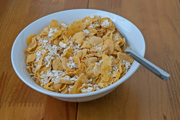 White bowl with a spoon, corn and oats flakes