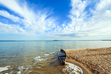 Old flooding boat on summer lake shore