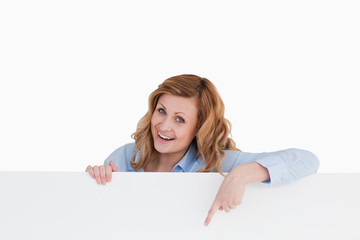 Happy blond-haired woman standing behind a white board