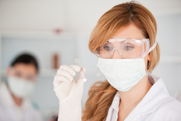 Blond-haired scientist wearing a mask and safety glasses and hol