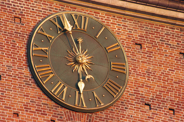 Golden clock in red wall of city hall tower in Krakow, Poland