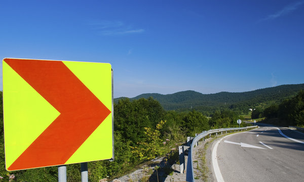 Big turning sign on a mountain serpentine by the road