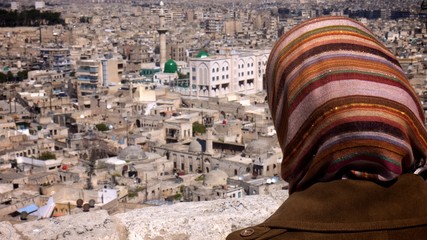 Woman wearing headscarf looking out over Aleppo