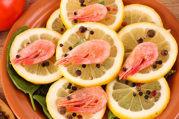 Shrimp on lemons with tomato, peppers and oil on wooden table