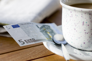 fünf Euroschein an einer Kaffeetasse