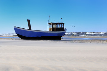 Obraz premium Fischerboot am Strand vor tosender See