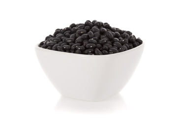 Black turtle beans in a bowl isolated on a white background.