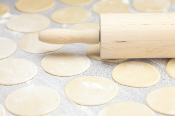 round shape of the dough and rolling pin with flour on the table