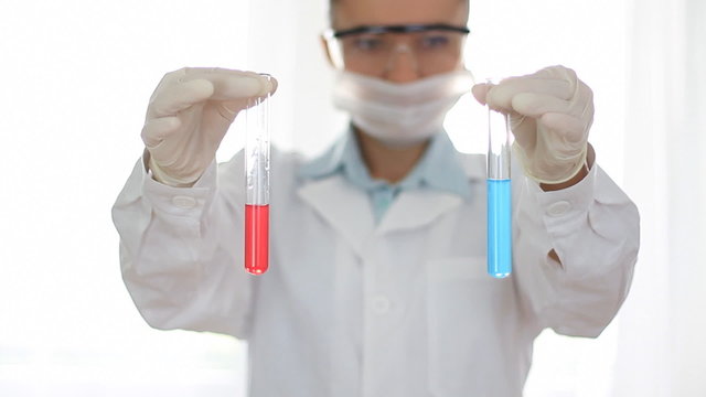 scientist hands holding test tubes with blue and red chemicals
