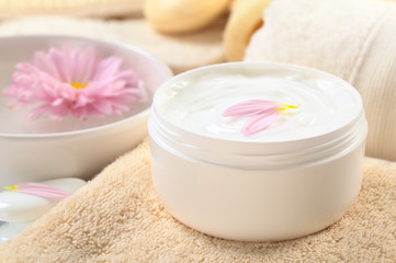 Fototapeta na wymiar Soft body, hand and face cream with pink petals