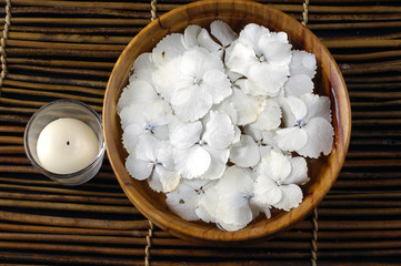 bowl of water with hydrangea petals and candle in glass