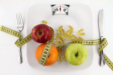 Fruits and vitamins with measuring tape on a plate