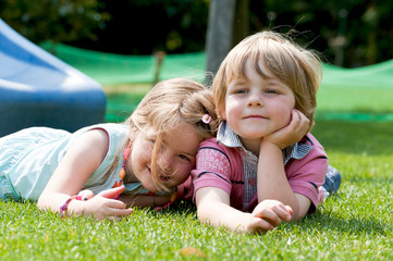 Zwei Kinder liegen auf dem Rasen