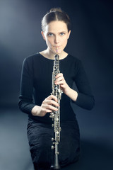 Young musician woman playing oboe musical instrument