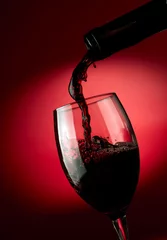 Fotobehang Red wine pouring in glass over dark background © SJ Travel Footage